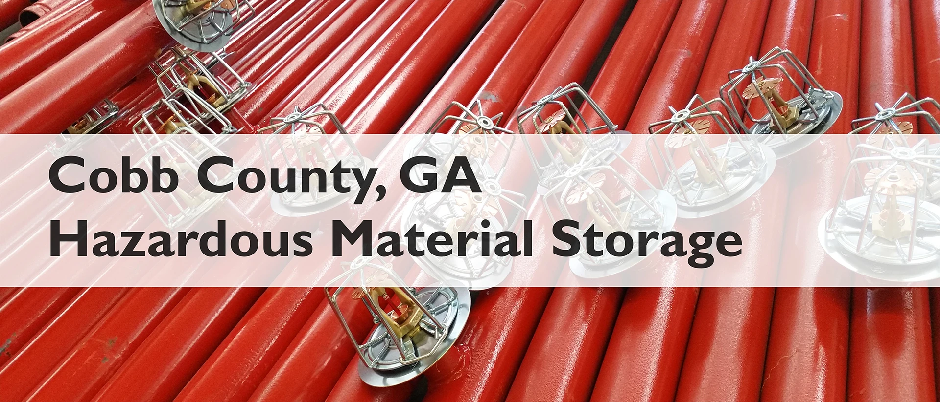 fire sprinklers and piping with the text "Cobb County, GA Tier II Hazardous Material Storage" on top of them. The text is black on top of a white bar that is 70% opaque to the sprinkler image below it.