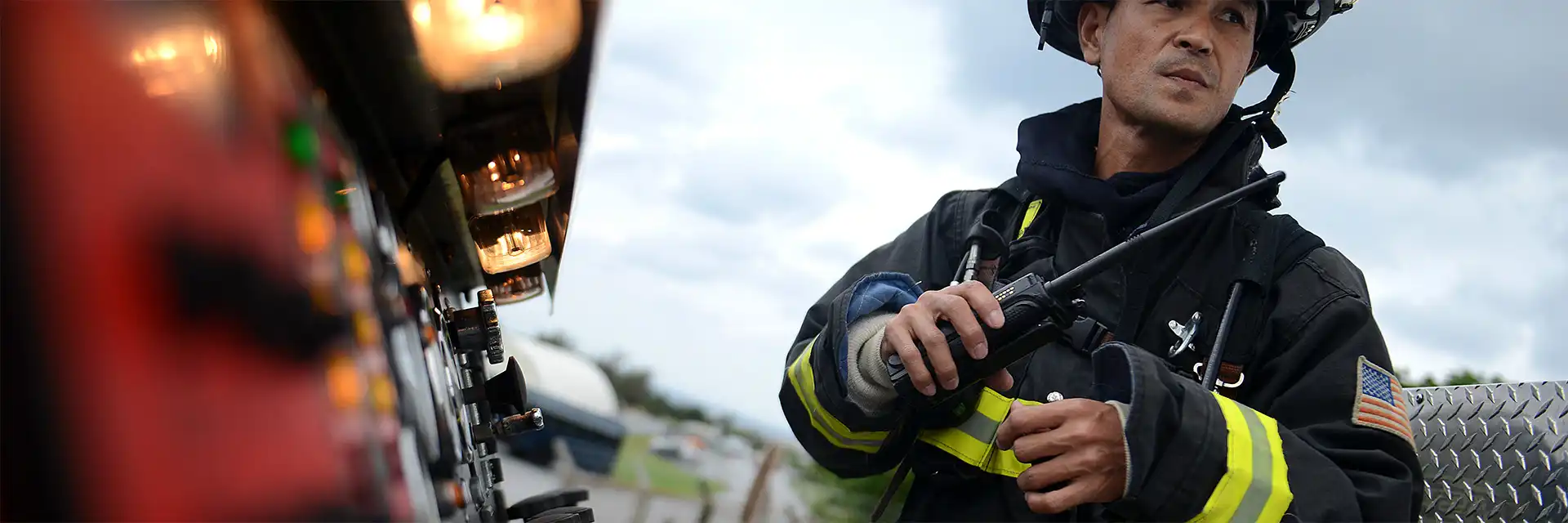 A firefighter holds his two-way radio while dress in a full firefighting uniforrm